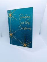 Load image into Gallery viewer, The Sending Love Christmas Card has a rich indigo blue background with a gold star motif. The message reads &quot;Sending love this Christmas&quot;.  
